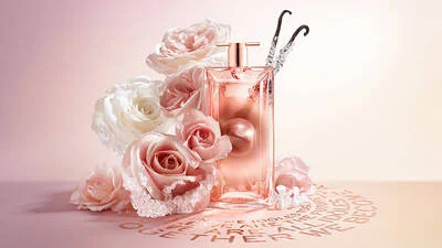 A perfume bottle surrounded by pink and white roses